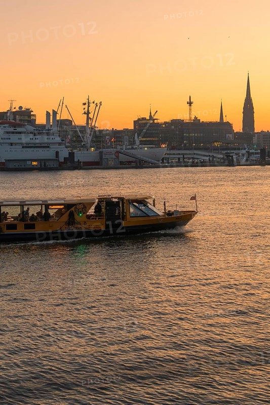 A ship on a river at sunset with the city silhouette in the background, Hamburg, Germany