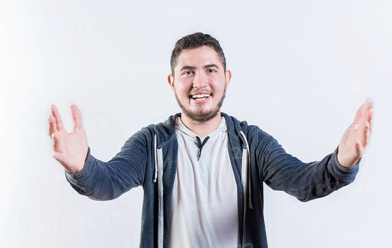 Friendly young man welcoming with open arms isolated. Hospitable guy opening arms to the camera