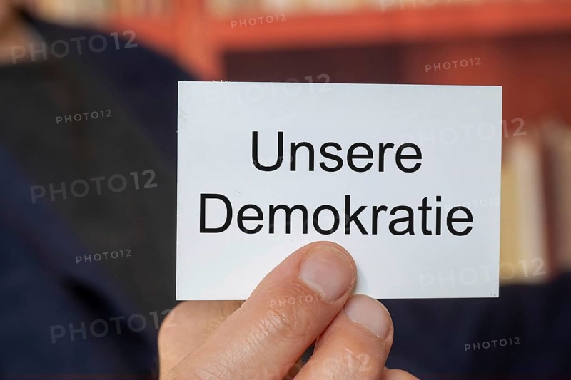 Man showing a business card with (added text) OUR DEMOCRACY (symbolic image)
