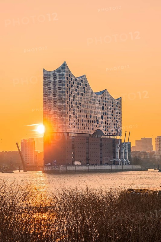 The sun rises behind the Elbphilharmonie and illuminates the surrounding area in golden colours, Hamburg, Germany