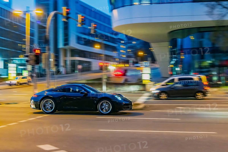 Porsche at night in front of urban surroundings with modern architecture, pull-along. Stuttgart, Baden-Württemberg, Germany