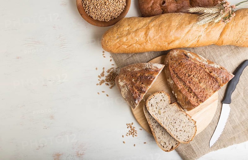 Sliced bread with different kinds of fresh baked bread on a white wooden background. top view, flat lay, copy space