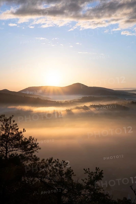 Mystical sunrise at the Wachtfelsen. Fascinating landscape shot between fog and clouds near Wernersberg, Pfälzerwald, Germany