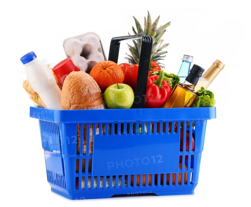 Plastic shopping basket with assorted grocery products isolated on white