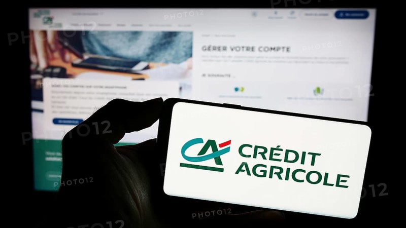 Stuttgart, Germany, 11-16-2023: Person holding smartphone with logo of French financial services company Crédit Agricole S.A. in front of website. Focus on phone display
