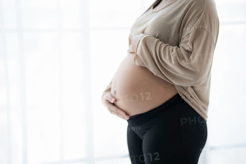 Pregnant woman holds hands on belly touching her baby caring about her health Beautiful happy pregnant woman tender mood photo of pregnancy