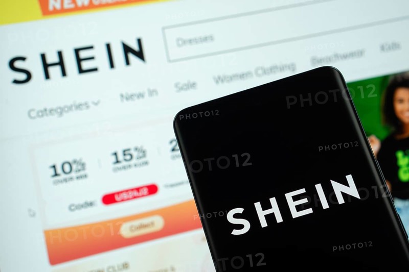 Dhaka, Bangladesh - 18 March 2025: The logo of the shein is displayed on a smartphone screen, and the website shein is visible on a computer screen in the background