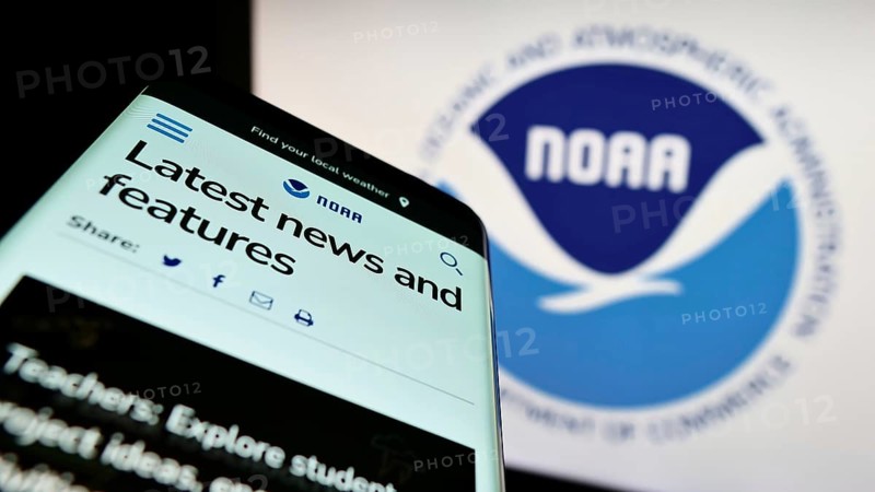 Stuttgart, Germany, 10-09-2022: Mobile phone with website of National Oceanic and Atmospheric Administration (NOAA) on screen in front of logo. Focus on top-left of phone display