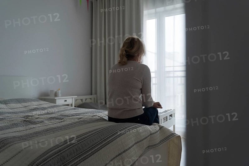 Mature woman sitting alone in the room, sad depressed person. Back view. mental health problemageing population.