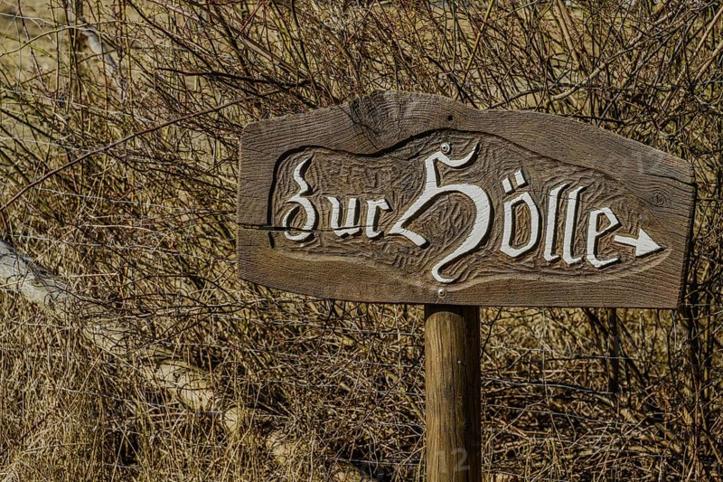A rustic wooden sign with the inscription 'Zur Hölle' stands at the edge of a thicket, Höllbachtal, Upper Palatinate
