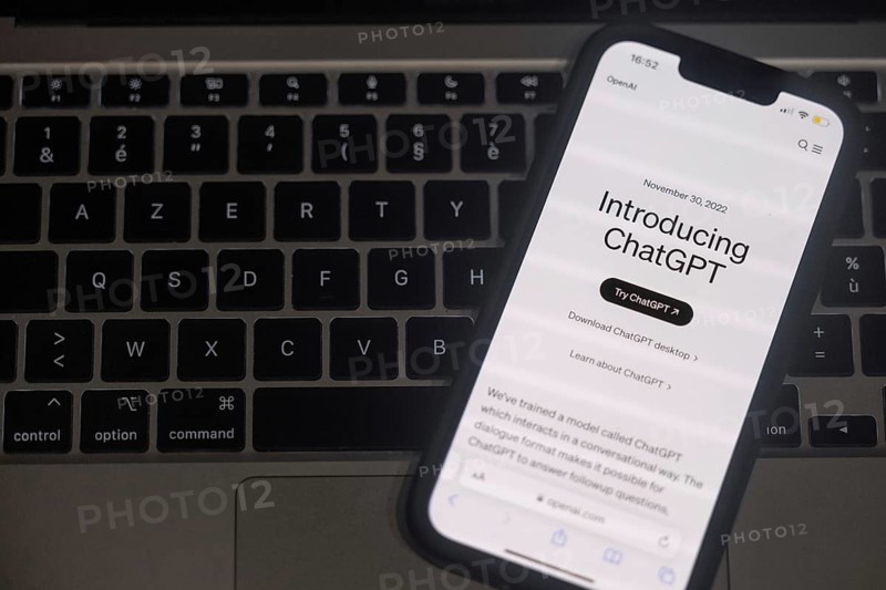 OpenAI software ChatGPT application on a mobile phone above a computer keyboard