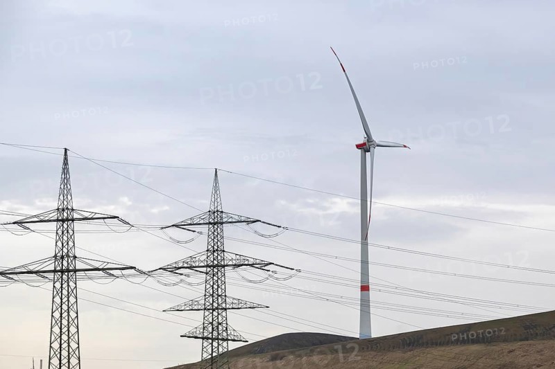 High-voltage pylons with wind turbine in german industrial landscape