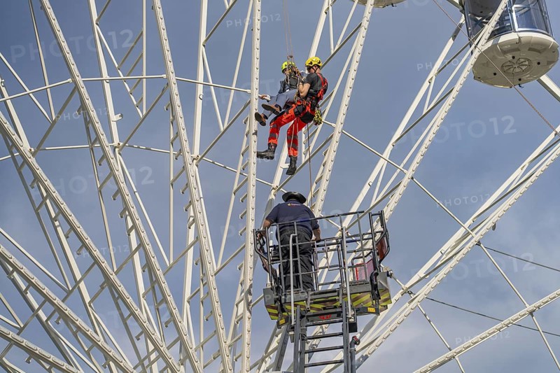 Two climbers and another worker during a rescue operation on the Ferris wheel, fire brigade exercise for gondola rescue, Germany