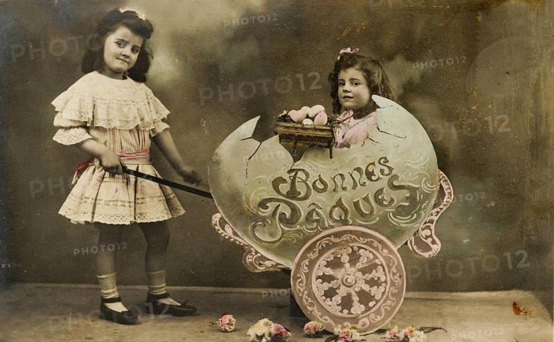 Child sitting in large egg, 1930s, Two girls in a vintage Easter photo with flowers and decoration, Historical photo