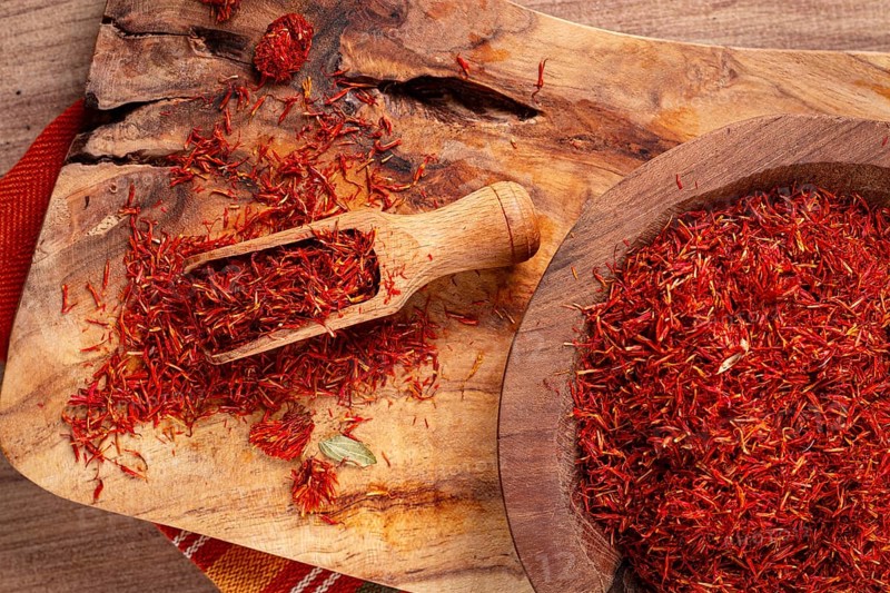 Spice saffron threads, in a wooden bowl, on a wooden table, top view, close-up