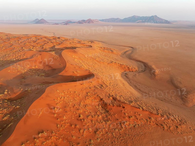 Sand dunes and isolated mountain ridges at the edge of the Namib Desert. Aerial view. Drone shot. Namibia
