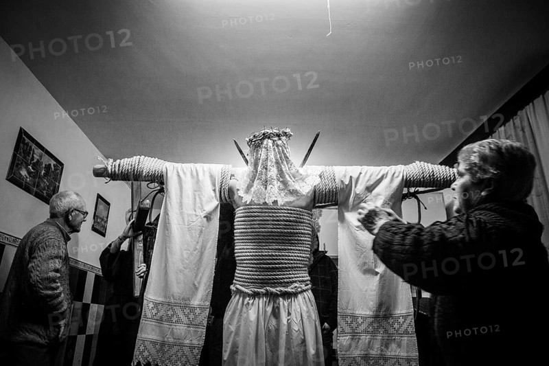 A man is tied to a cross with hemp ropes, he carries two swords in his back, a shroud over them, on his head he wears a crown of thorns, he prepares for the procession of the Empalaos, every Maundy Thursday in Holy Week, Valverde de la Vera, Extremadura, Spain