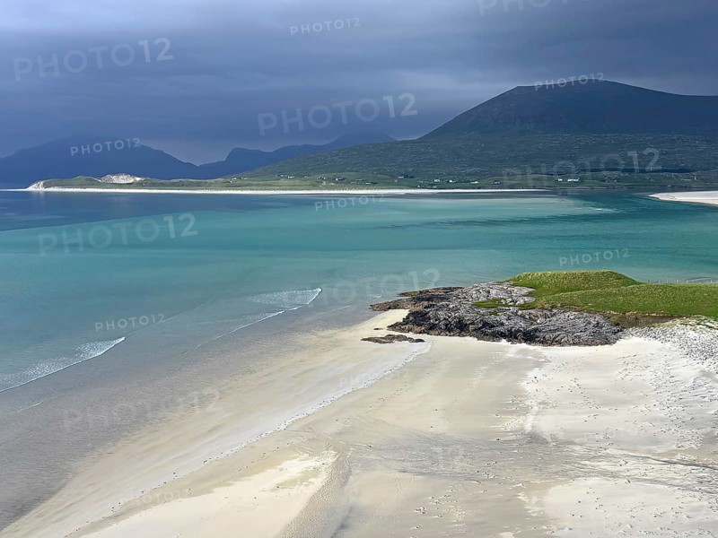 Dramatic sky over a calm beach with turquoise water and mountains in the background, Outer Hebrides, Isle of Harris, Scotland, United Kingdom