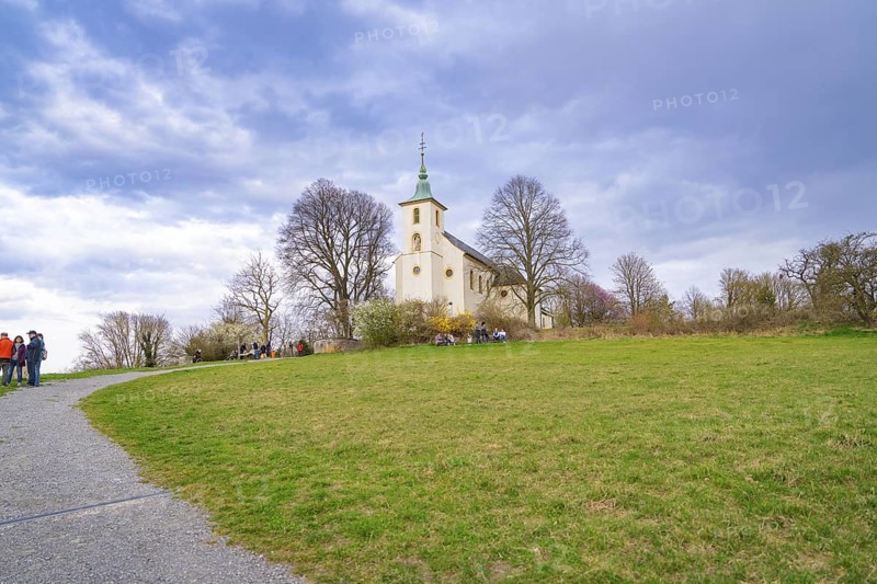 Small church on a hill, surrounded by trees and a green meadow, with a cloudy sky, Michelsberg, Germany
