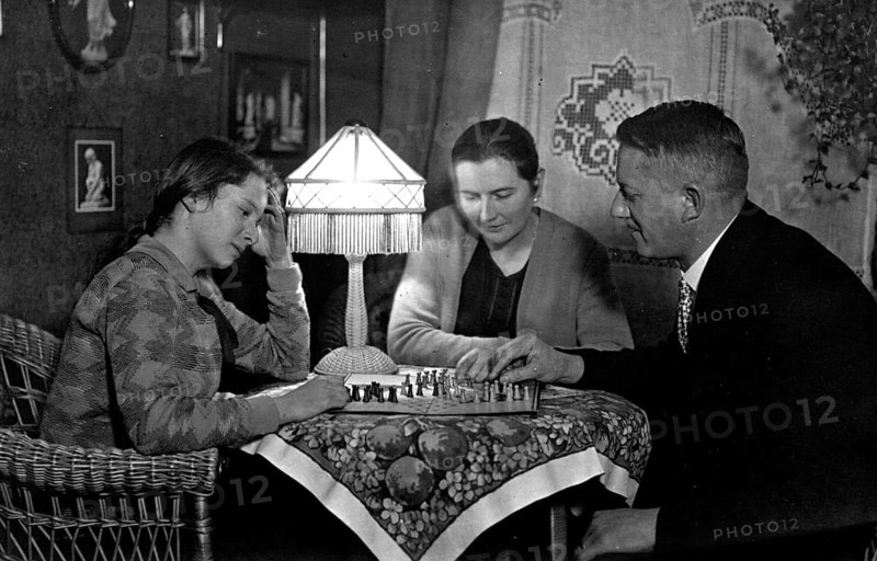 1920 Halma game, family playing chess in a cosy living room, historical photo