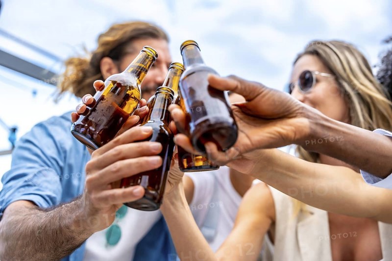 Group of friends celebrating on a rooftop, raising their beer bottles high for a joyful toast, embodying happiness and togetherness