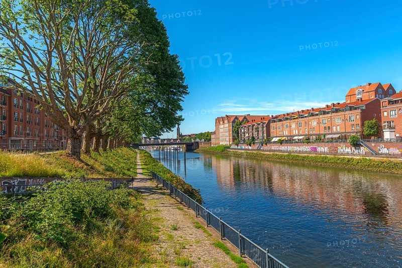 View from Alte Neustadt across the Weser to the Teerhof peninsula, brick architecture, hiking trail, row of trees, water reflection, cultural church St. Staphani, blue sky, Hanseatic City of Bremen, Germany