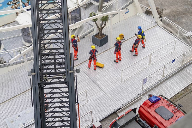 Several firefighters stand on a platform next to a crane jib, fire brigade exercise for gondola rescue, Germany