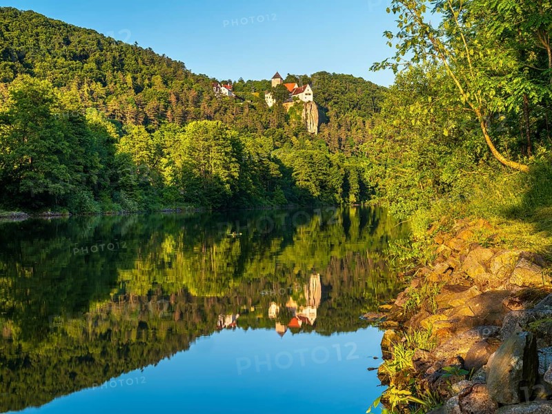 Prunn Castle on a steep cliff above the Altmühl Valley in the evening light, reflection in the river Altmühl as part of the Main-Danube Canal, near Riedenburg, Altmühl Valley nature park Park, Lower Bavaria, Germany