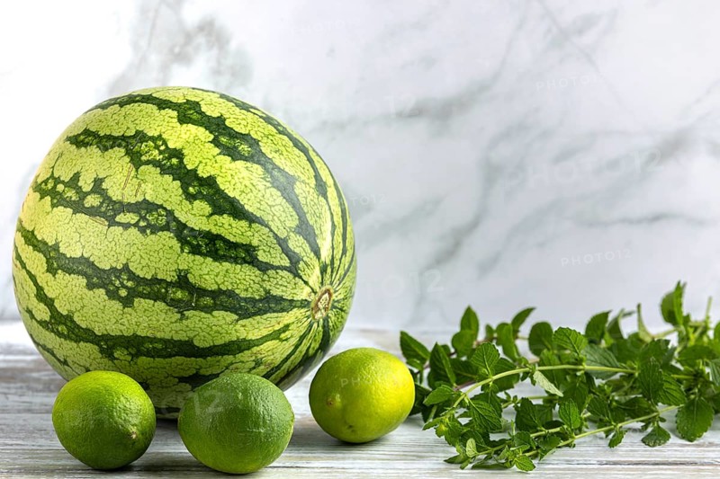 Watermelon and limes with mint leaves on a wooden surface