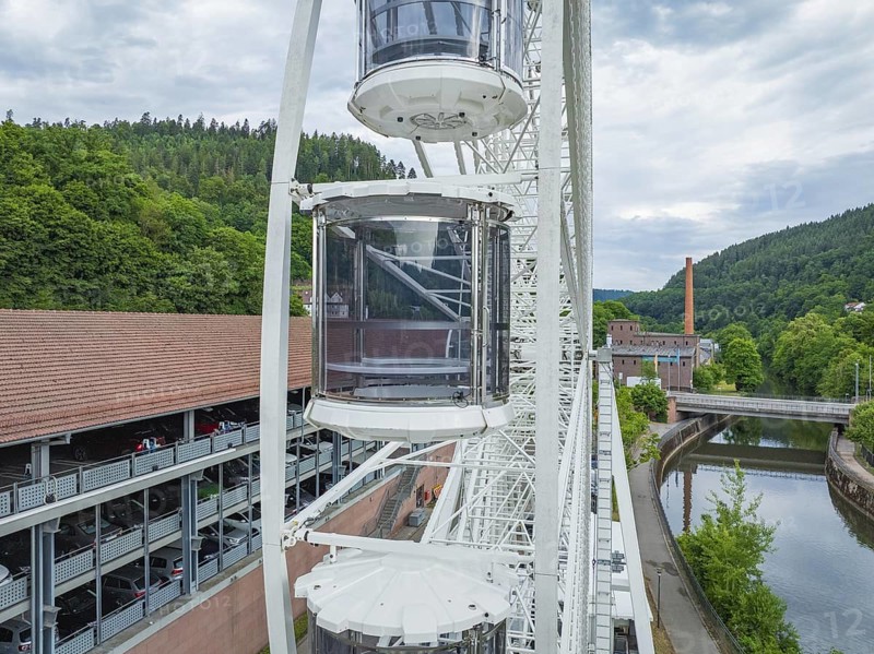 Ferris wheel with gondolas next to a building and a river, Ferris wheel construction for the 950th anniversary of the town of Calw, Black Forest, Germany