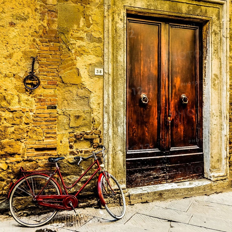 Red bicycle leaning against a wall in Pienza