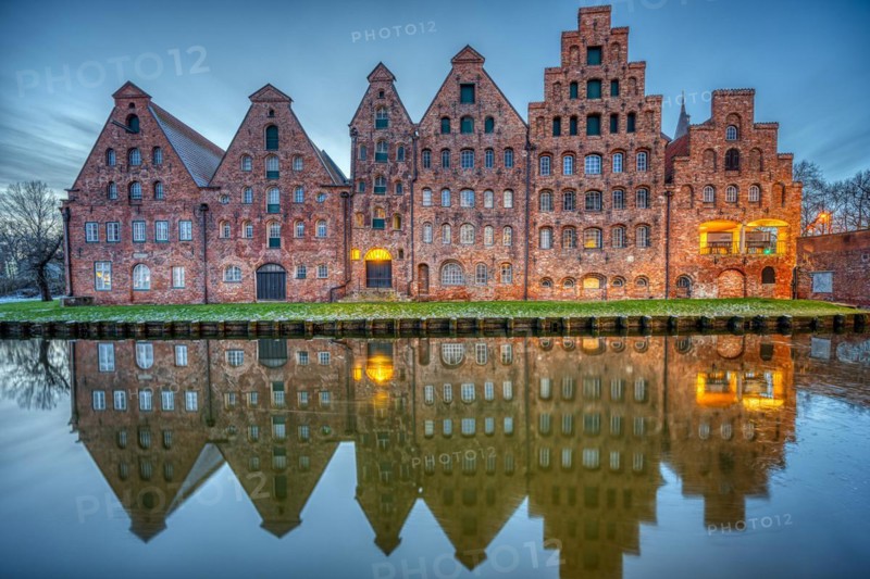 The historic salt warehouse reflected in the Trave river at dusk, seen in Lübeck, Germany