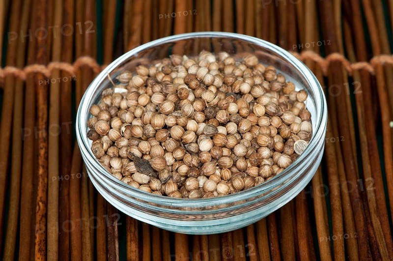 Dried coriander in a bowl on wooden base