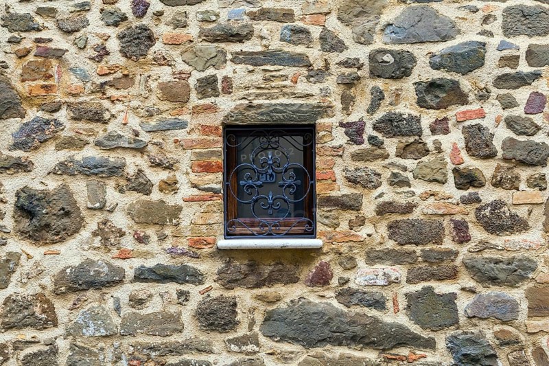 Cloudy autumn day in Tuscany. The small town of Montalcino. The beautiful decor element of a small window - metal window grill. The concept of cognitive, active and photo tourism