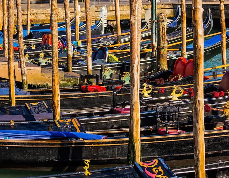 Magical journey to Venice. Gorgeous varnished gondolas offer a getaway on the Grande Canal. Bright sunny morning in Venice. The concept of active, cultural and photo tourism