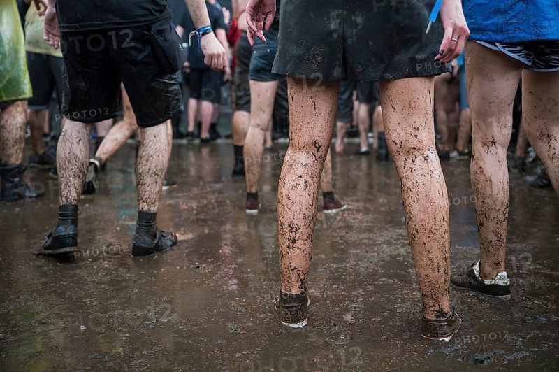 Dirty legs of people dancing in the mud during concert