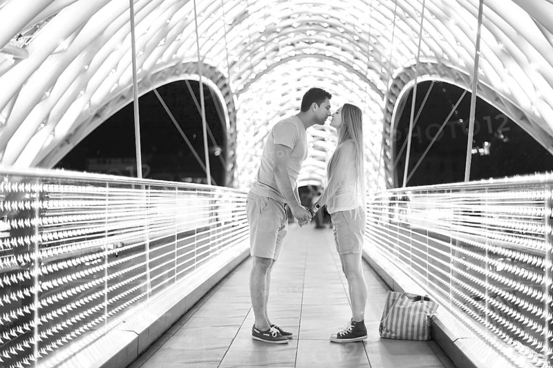 Young loving couple kissing on the bridge of Peace in Tbilisi, Georgia