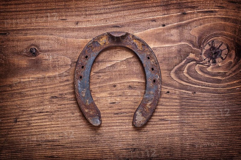 Single old horseshoe on vintage wooden board happy concept