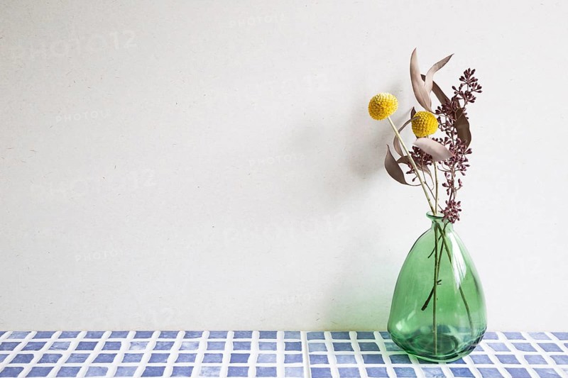 Vase of dry flowers on blue ceramic mosaic tile table. white wall background. Home interior