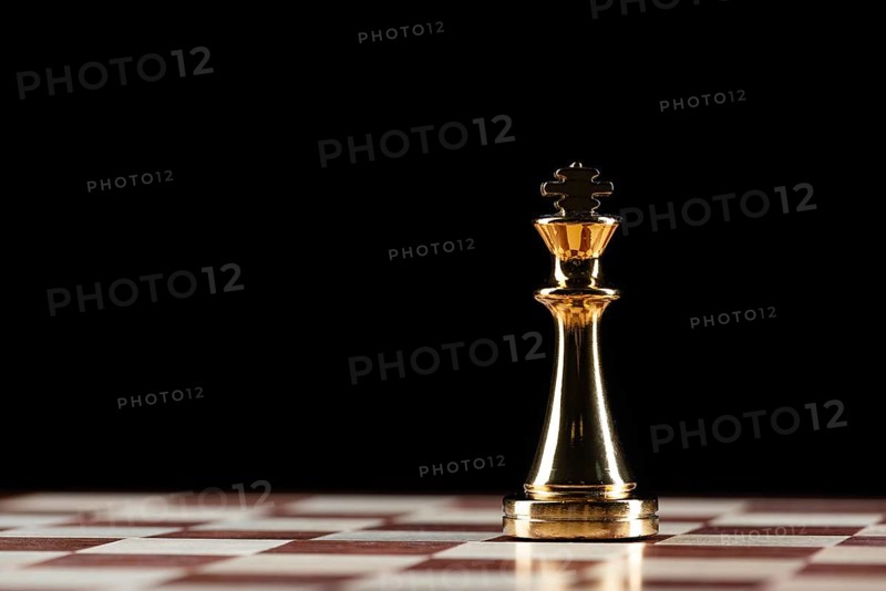 Golden king chess figure standing on chessboard. Intellectual and tactic game. Strategy planning, leadership and teamwork business concept. Close-up one gold chess piece on black background