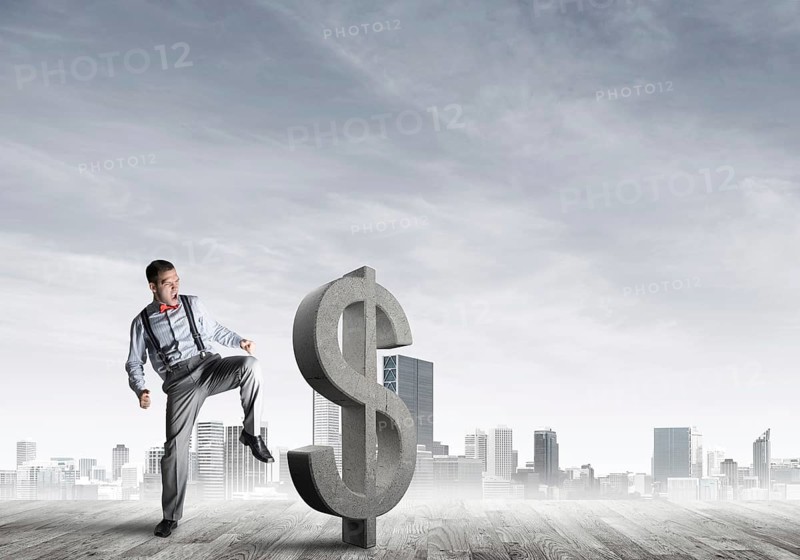 Determined banker man against modern cityscape breaking dollar cement figure