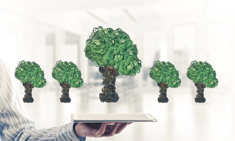 Close of businessman holding tablet pc with green tree made of gears and cogwheels. Mixed media