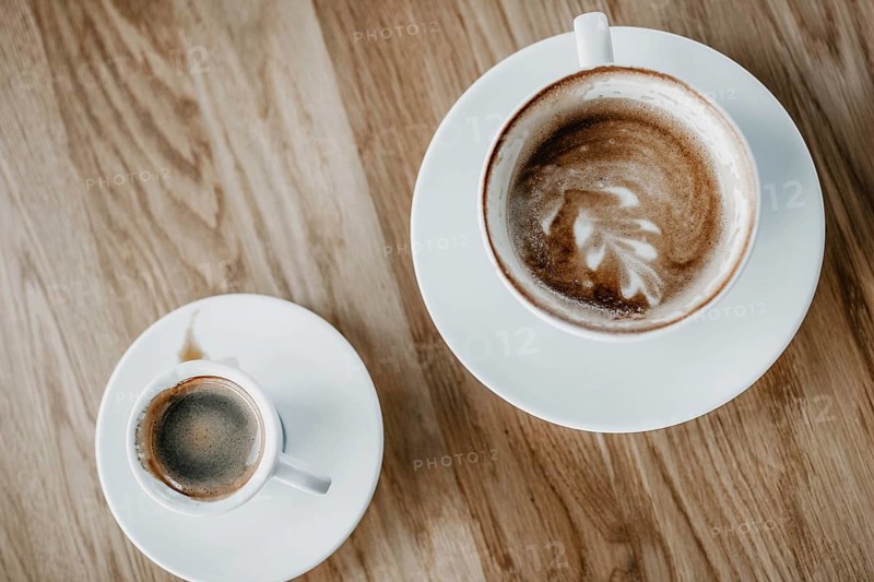 Top view of a cappuccino with latte art and an espresso on a wooden table