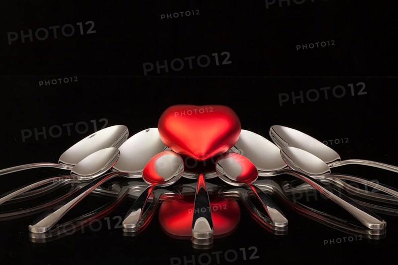 Nine spoons and red heart on a black glass desk