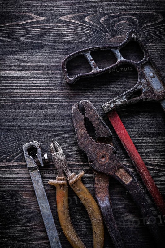 Rusty vintage hacksaw nippers pliers on wooden board construction concept