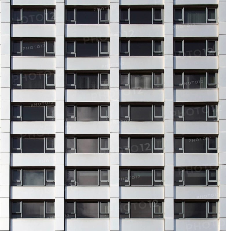 Front view of the facade of a modern commercial building with geometric repeating windows and grey cladding