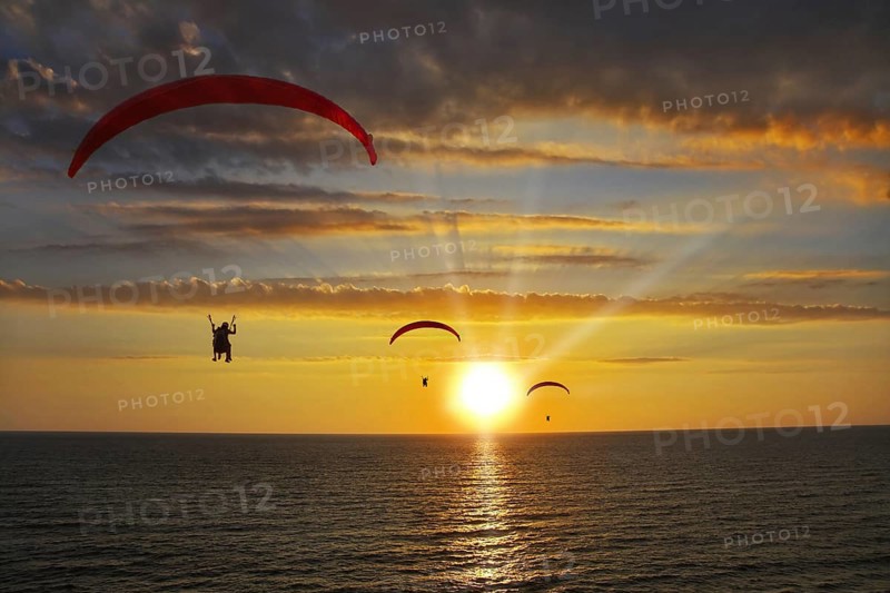 Operated parachutes above the sea on a sunset