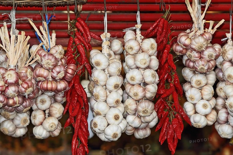 Bundles of garlic and bundles of cayenne pepper hanging on wicker fence of the southern market