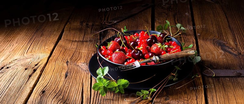 Bowl with different fruits such as strawberry, red currant, and cherry