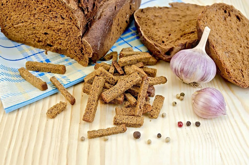 Rye homemade bread, crackers, garlic, pepper peas, blue cloth on a background of wooden boards